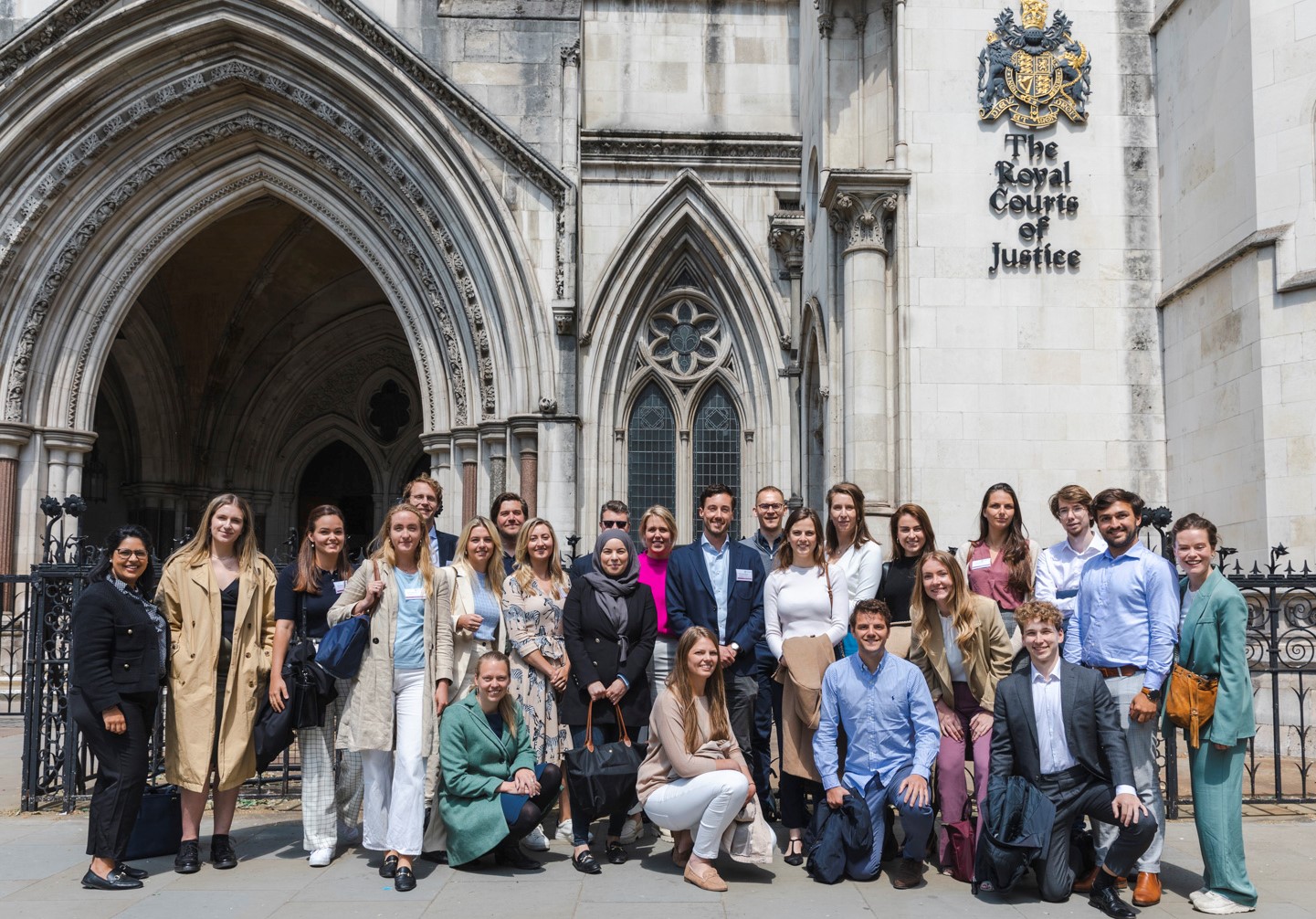 A group of smartly dressed people outside the Royal Courts of Justice building.