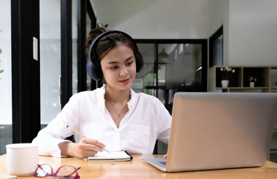 A photo of a person at a table with a notepad and a laptop 