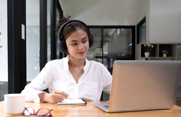 A photo of a person at a table with a notepad and a laptop 