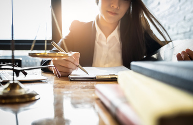 Woman writing on paper on a desk.