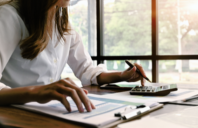 A photo of a person at a desk with a clipboard and a calculator