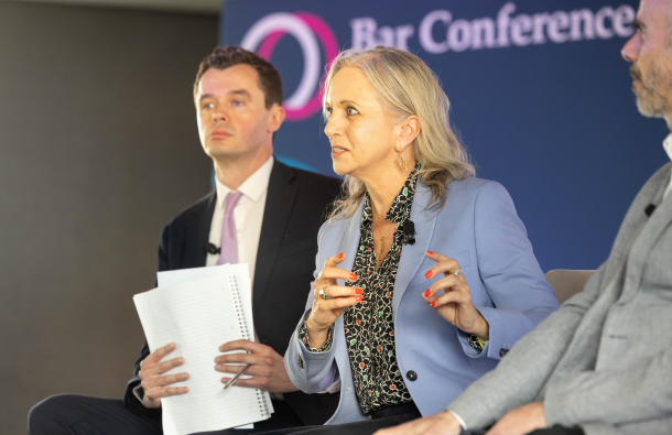 A photo of three people on a stage, one person talking towards an audience off-camera
