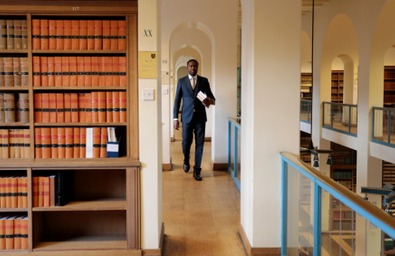 A black barrister walking down a chambers hallway