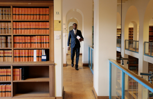 A black barrister walking down a chambers hallway
