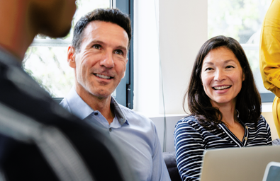 People smiling and sitting at a table with laptops