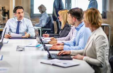 People sitting around a table in front of laptops