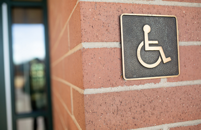 A photo of a wall outside a building with a disabled sign on it