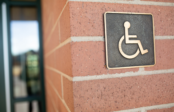 A photo of a wall outside a building with a disabled sign on it
