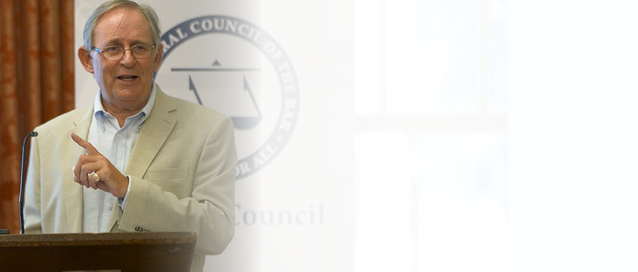 A photo of a person standing at a lectern pointing his finger in the air and talking
