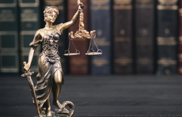 A bronze statue of Lady Justice in front of  books.