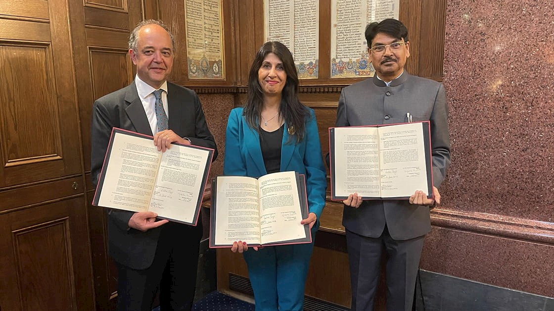 Nick Vineall KC, Lubna Shuja, and Manan Kumar Mishra holding signed documents