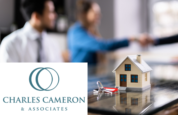 A photo of three people around a table with a miniature house and set of keys on it, two people shaking hands - Charles Cameron logo on the top