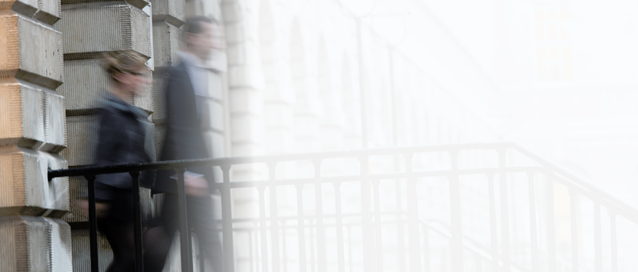 A photo of two people walking towards an outdoor staircase outside, there is a faded white backdrop beyond them
