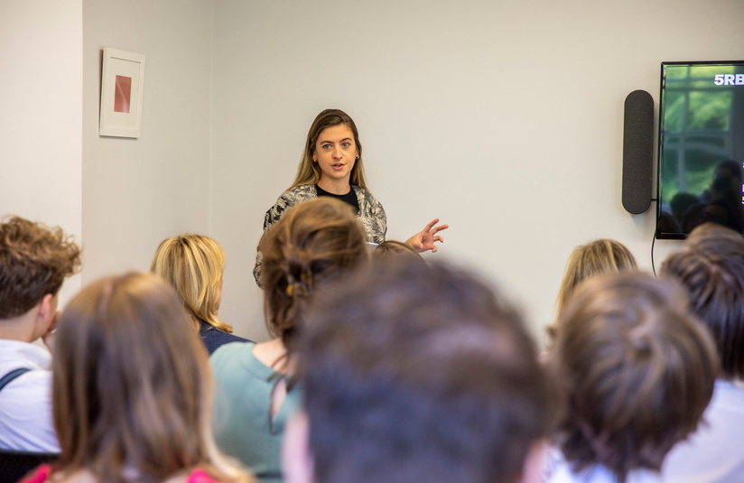A photo of a group of people watching one person talk